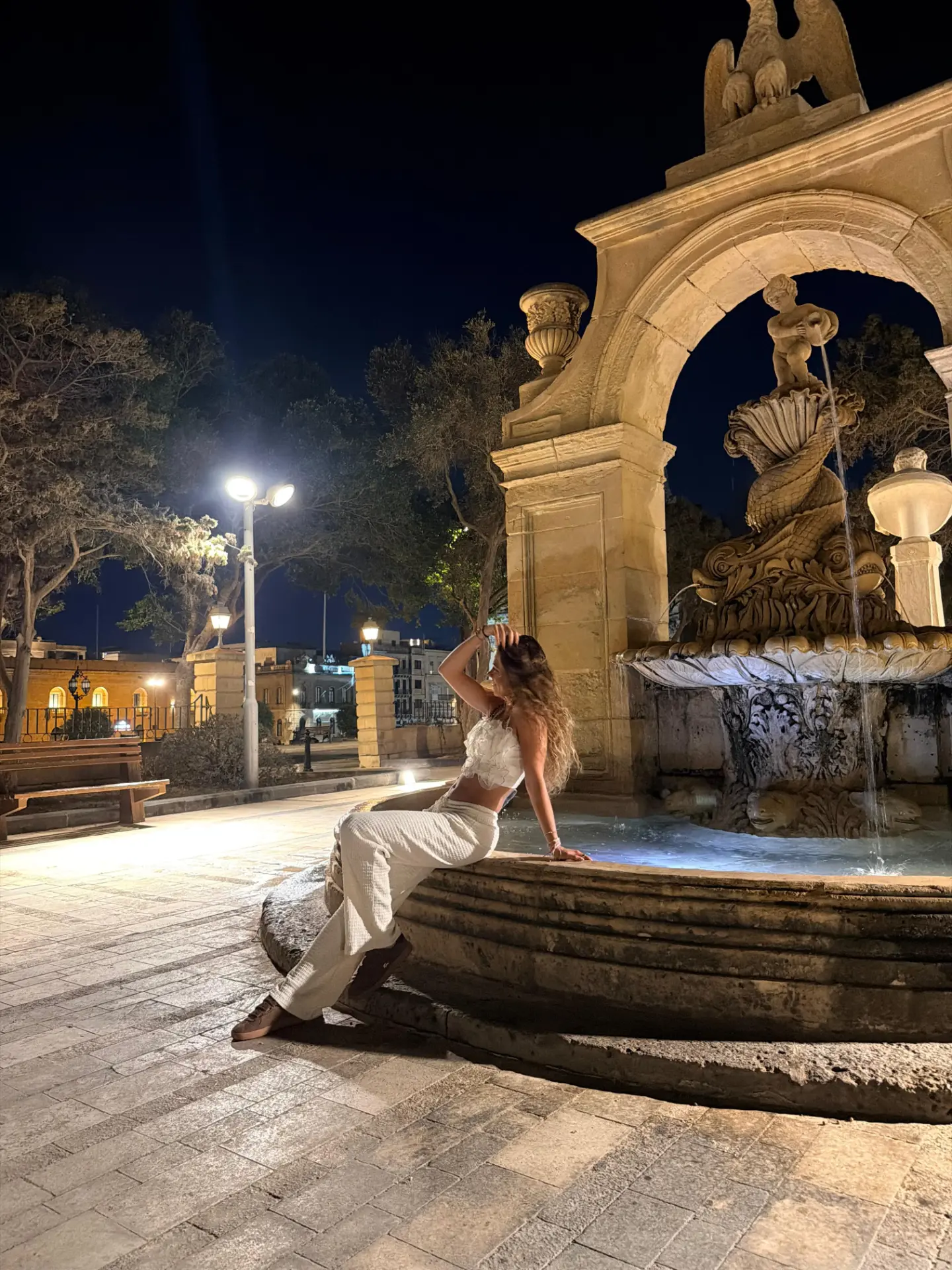 Liv Leivo by a lit stone fountain at night
